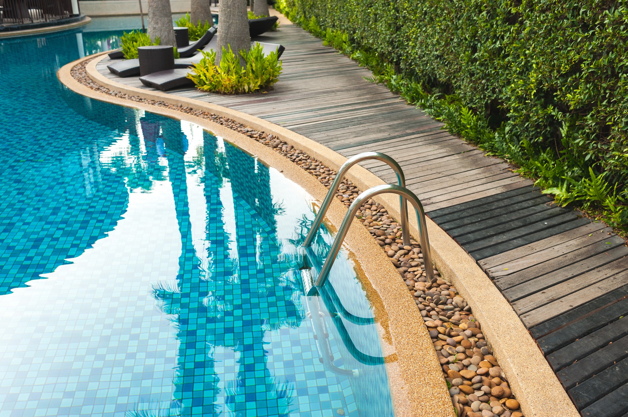 Hotel swimming pool with sunny reflections Swimming pool of luxury hotel Swimming pool and wooden deck ideal for backgrounds