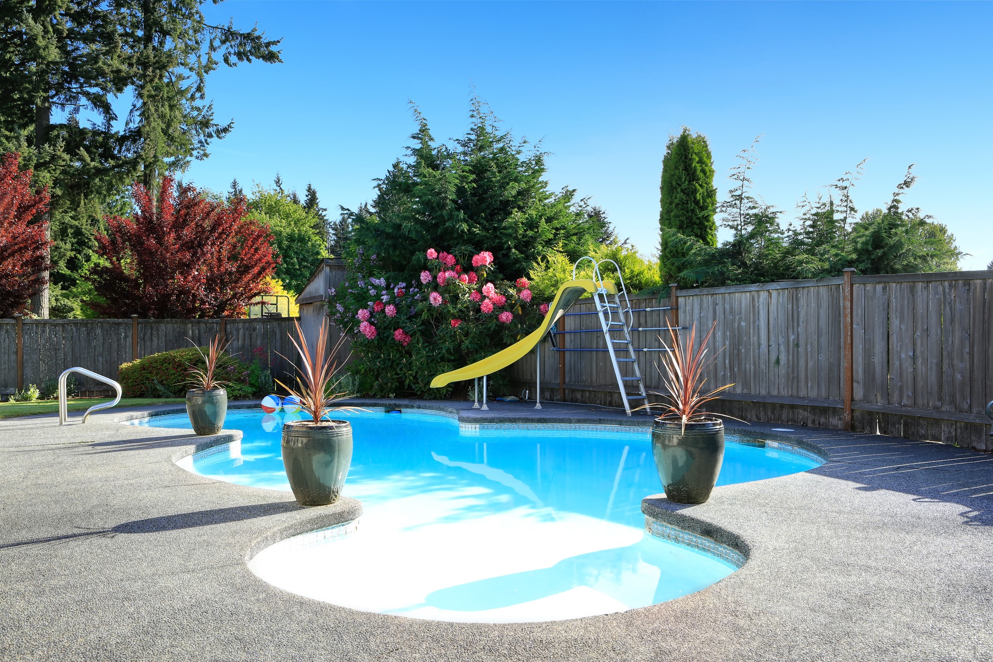 Fenced backyard with small beautiful swimming pool and playground