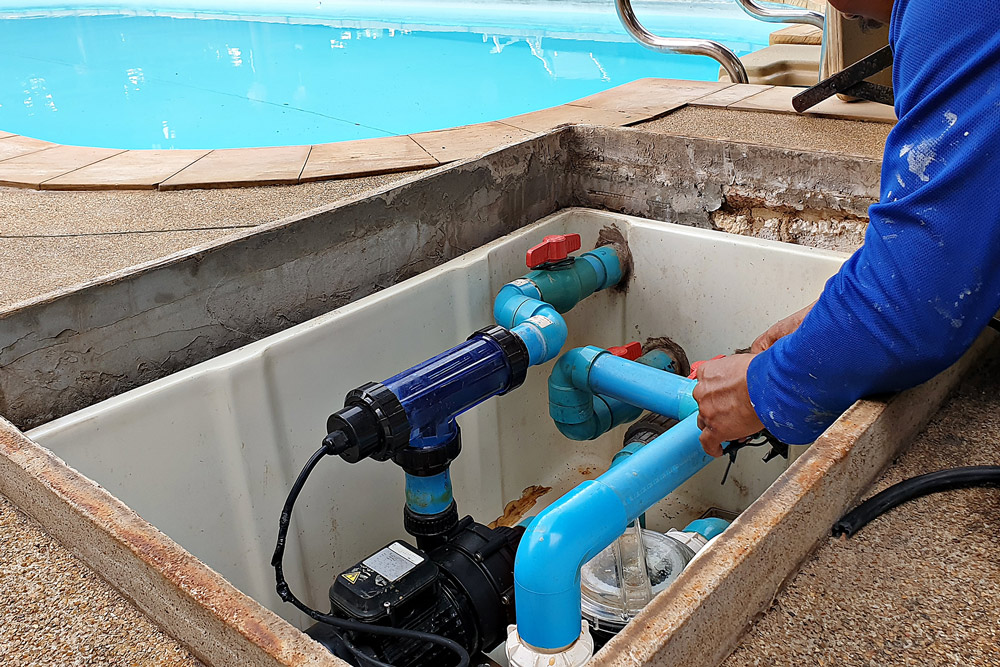Working on pool plumbing inside an open maintenance compartment